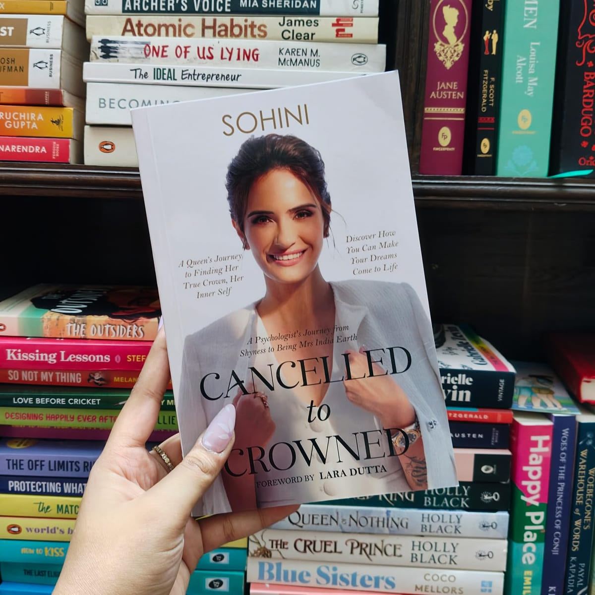 A hand holding Cancelled to Crowned in a bookshop